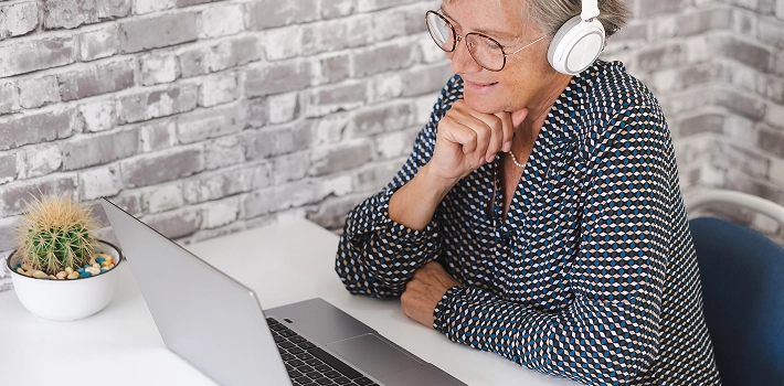 Older woman living in a retirement village working on her laptop from her home office.